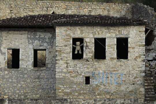 Abandoned building in Berat Castle, Albania, with a teddy bear in a window, loss and forgotten childhood