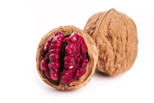 Red-skinned Xinjiang walnuts with crimson kernel meat on white background - premium quality nuts from China