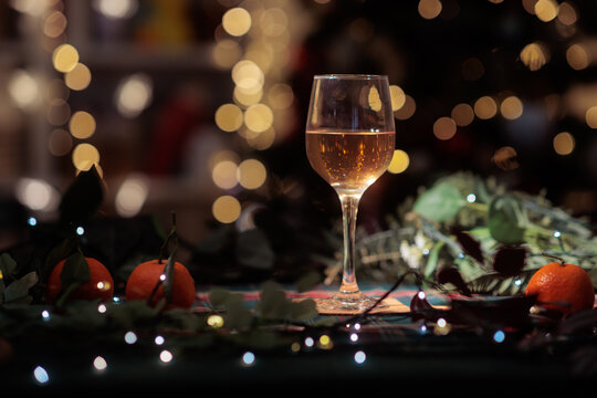 Elegant Wine Glass Filled With Rose Beverage On Festive Table. Crystal wineglass stands among Christmas decorations against bright holiday d&eacute;cor 