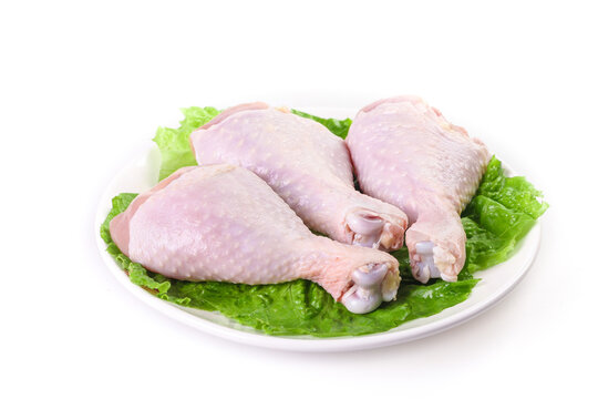 Raw Chicken Drumsticks and Thighs on White Plate with Fresh Lettuce