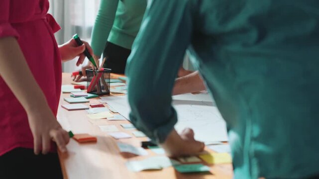 Close up of developer team using mind map to brainstorm idea. Top view of skilled group of business people working together writing marketing strategy by using markers and sticky notes. Symposium.