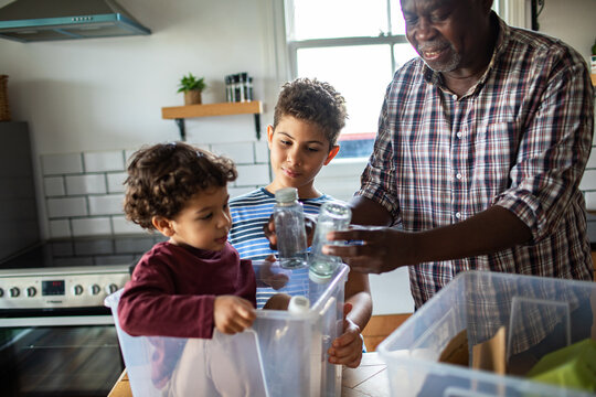 Older man and children recycling glass jars at home