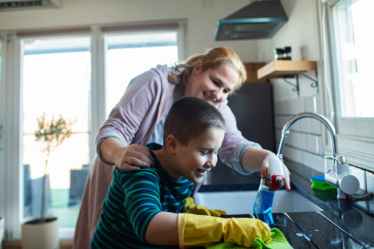 Mother and son cleaning kitchen counter at home