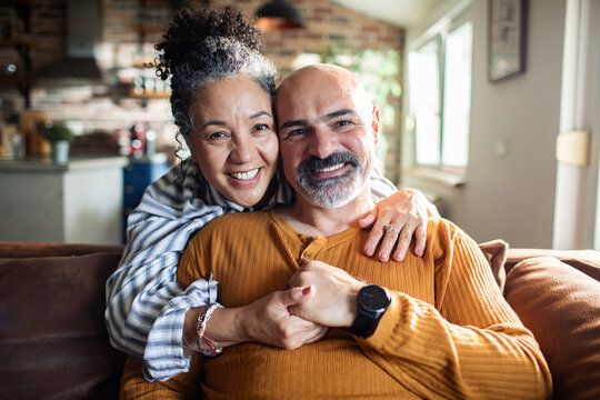Happy mature couple hugging on couch at home