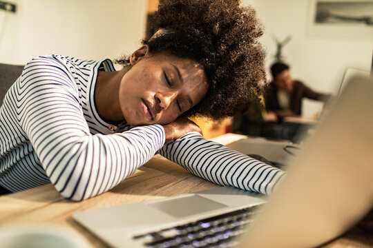Tired woman sleeping at laptop in home office