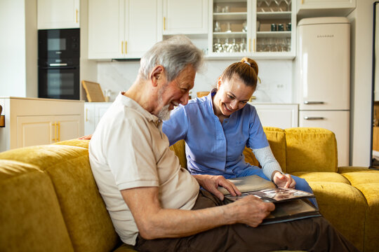 Caregiver helping senior review photo album at home