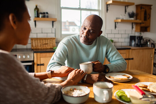Mature couple talking over coffee at home kitchen table
