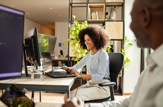 Smiling woman working on laptop in modern open office