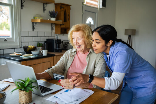 Caregiver helping senior woman with online banking at home