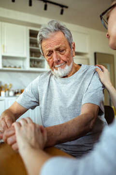 Elderly man comforted by caregiver at home