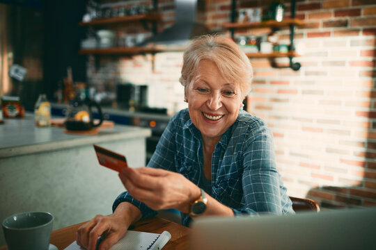 Senior woman making online payment at home kitchen