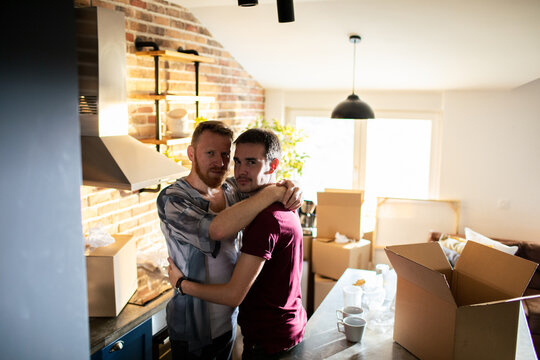 Affectionate couple hugging while moving boxes in kitchen