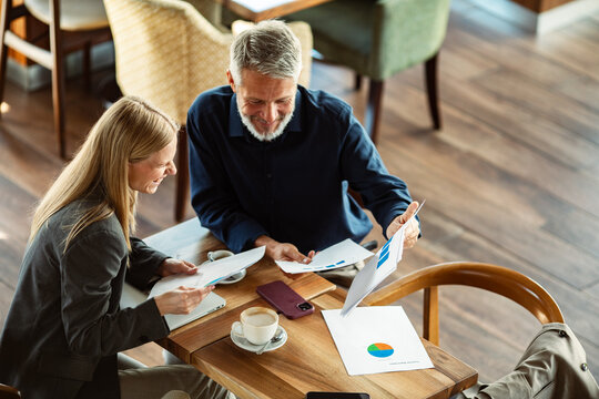Two colleagues reviewing financial charts at a coffee shop