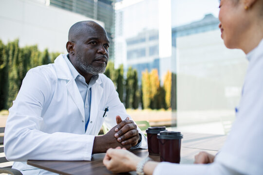Doctors having coffee and discussion outdoors at hospital