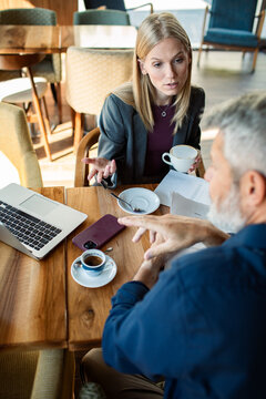 Two business colleagues discussing project over coffee at cafe table