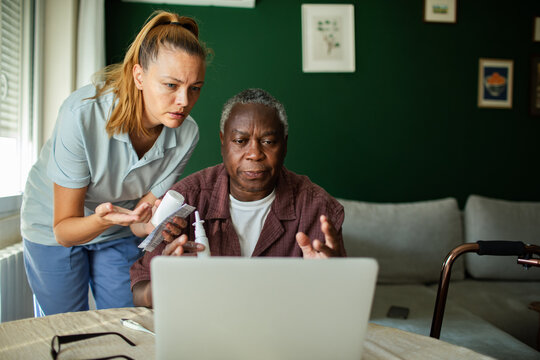 Caregiver assisting senior with telehealth at home