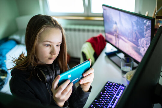 Teen gamer playing mobile game at home desk