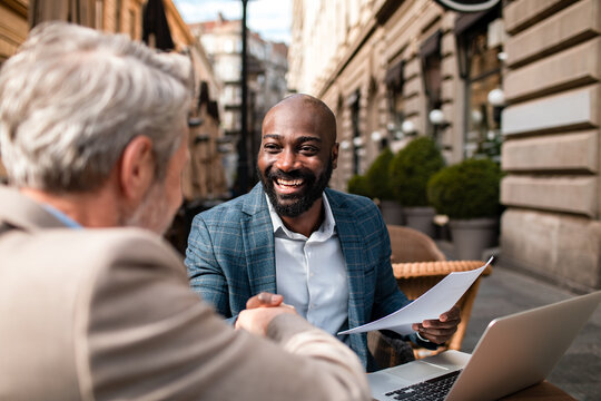 Two business professionals shaking hands at outdoor cafe meeting