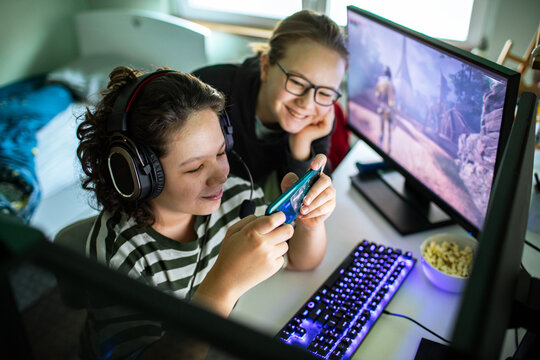 Two teens playing mobile game at home