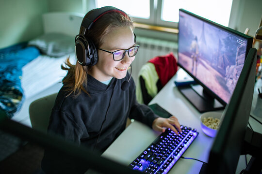 Smiling teen girl gaming on pc at home