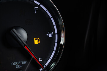 Fototapeta premium Fuel gauge with warning indicating low fuel tank on car dashboard