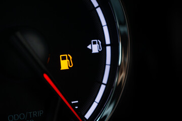 Naklejka premium Fuel gauge with warning indicating low fuel tank on car dashboard