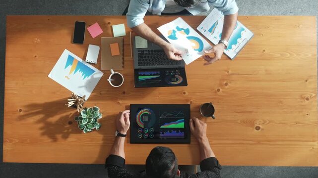 Male leader use laptop to analysis graph while marketing team working on tablet and looking at financial chart. Top view of startup group finding solution and planning strategy together. Convocation.