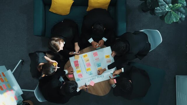 Top down view of business people hands making scrum task board to manage workflow in workplace. Diverse marketing team drawing a line and use colorful stick notes to work on kanban. Directorate.