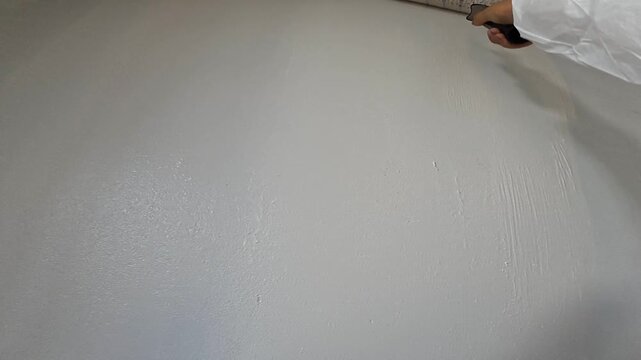 Applying White Paint with Roller During Interior Renovation