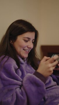 young Woman Playing Handheld Gaming Console While Relaxing on Bed at Home