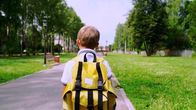 Boy walks away, yellow backpack on his back. Green park paths and trees frame his journey. Sunlight glows softly on the scene. He moves confidently, ready for new adventures ahead