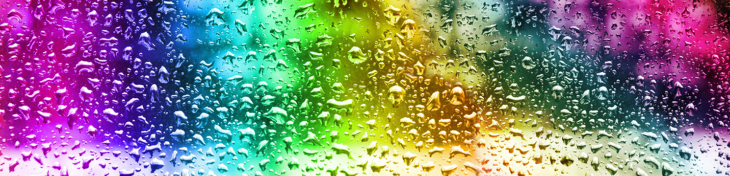 Raindrops on a window create colorful patterns in a bright setting during the day