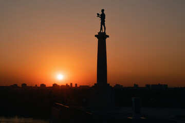 Fototapeta premium Belgrade, Serbia - August 4, 2026:Silhouette of the Pobednik monument and the city with a beautiful sunset...