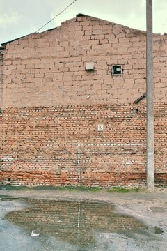 Old brick wall reflecting in a puddle on wet asphalt