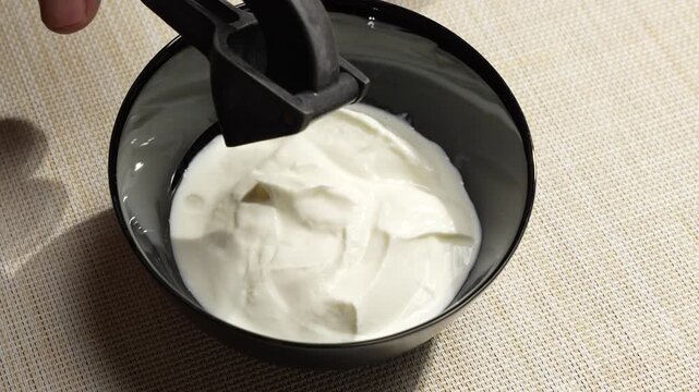 Pressing Fresh Garlic Into a Creamy Yogurt Sauce