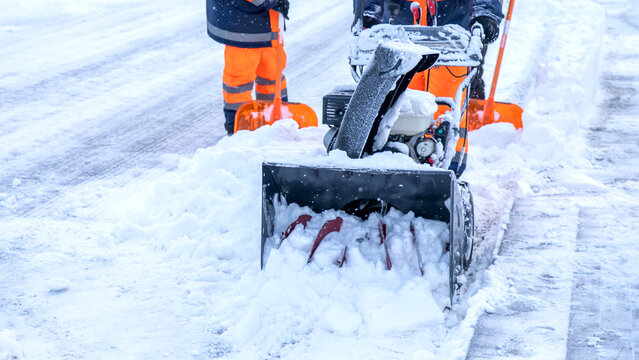 Snowblower clears thick snow from a sidewalk
