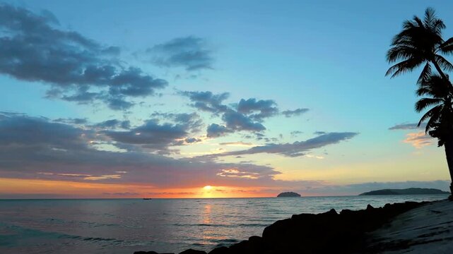 Spectacular sunset over the sea with aplm trees silhouettes in Malaysia