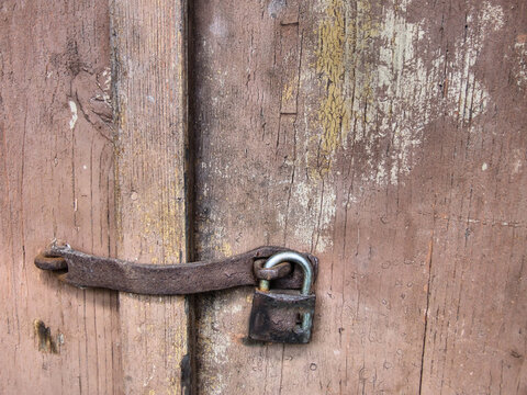 Old rusty latch and padlock on a weathered wooden door