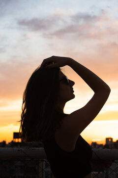 Teenage girl enjoying contemplative sunset cityscape moment on rooftop