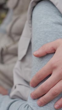 Fingers curl lightly as they rest atop gray material. Gray pants texture is consistent under gentle weight. Steady camera captures close up view without movement focusing