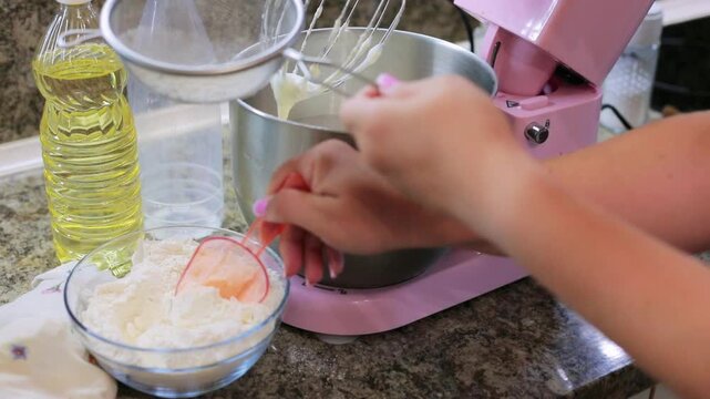 Sifting flour through a sieve into a mixer bowl while preparing homemade dough, an essential baking step in the kitchen alongside cooking oil
