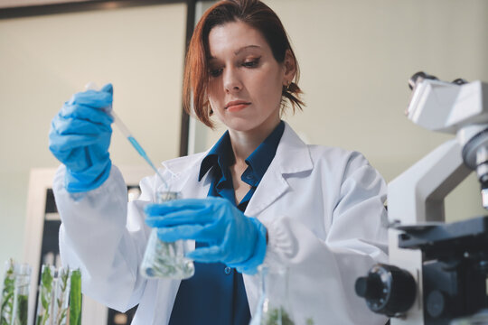 Scientists in lab coats work with plants in a modern lab, focusing on research and experimentation under bright, sterile conditions.