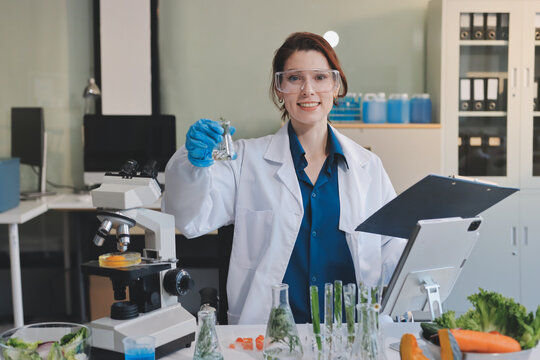 Scientists in lab coats work with plants in a modern lab, focusing on research and experimentation under bright, sterile conditions.