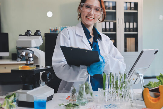 Scientists in lab coats work with plants in a modern lab, focusing on research and experimentation under bright, sterile conditions.