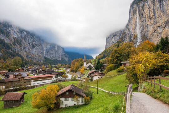 Lauterbrunnen alpine village houses with Staubbach Falls and steep cliffs in autumn. Lauterbrunnen, Canton of Bern, Switzerland.