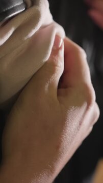 Hands held tightly in close view with moles visible. Interaction between hands emphasizes grip strength. Out of focus backdrop maintains focus on primary elements