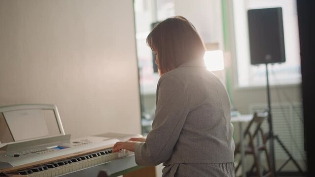 Pianist playing keyboard in studio, soft sunlight on keys and speaker, teacher demonstrating phrasing, focused posture and slow rehearsal, calm tempo and warm atmosphere for lesson prep