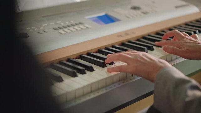 Closeup white student hands practicing piano scales on digital keyboard, illuminated display, patient tutor observation from foreground, steady tempo, diligent repetition, indoor lesson mood