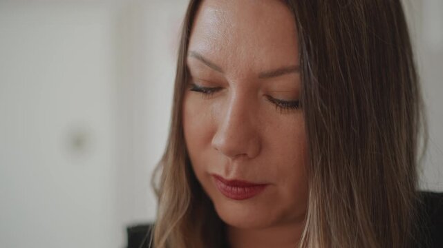 Woman coach in quiet studio reviewing vocal notes and listening closely, closeup portrait with serious expression, soft diffuse light creating intimate mood, sheet music and session planning visible,