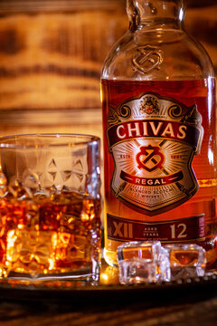 Vertical Chivas Regal 12 bottle and whisky glass create a premium bar composition.